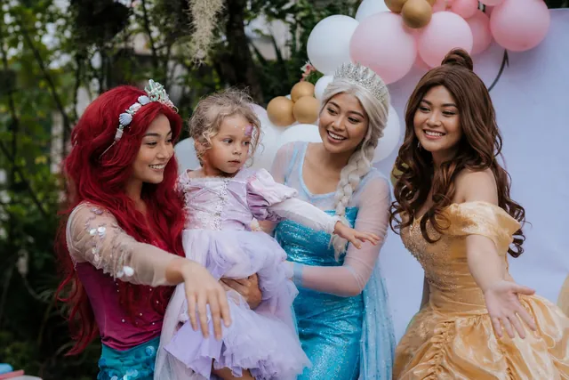 Princess characters playing with a toddler girl at a Bali party