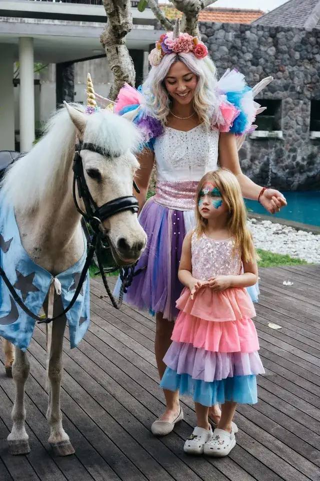 Unicorn fairy and pony with a face-painted girl at a Bali kids party