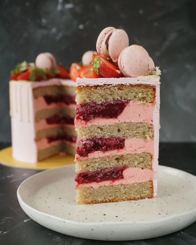 Slice of vanilla berry birthday cake topped with macarons