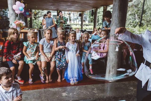 Group of kids amazed by a giant soap bubble during a bubble show in Bali