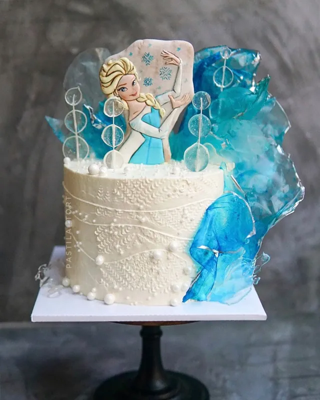 Elsa-themed white birthday cake with blue sugar ice