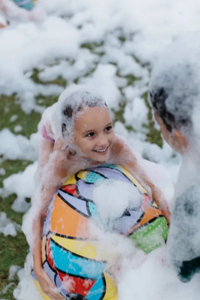Girl with a beach ball laughing in the foam at a Bali kids foam party