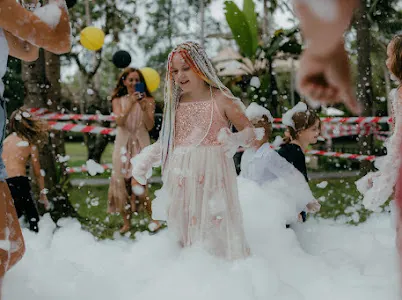 Girl in a party dress walking through foam at a kids party in Bali