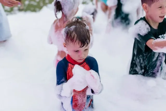 Little boy playing with foam at a daytime kids foam party in Bali