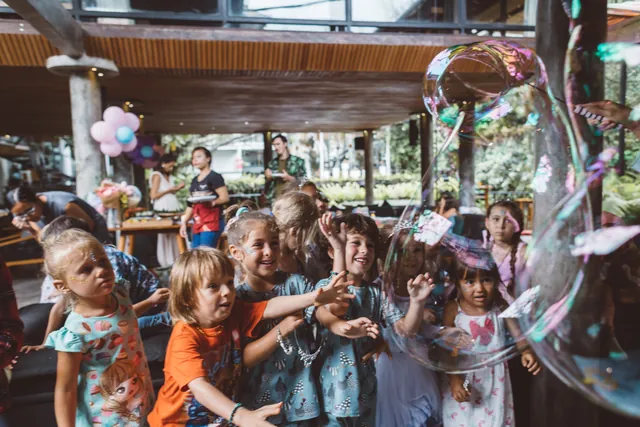 Children reaching for a giant bubble at a birthday party in Bali