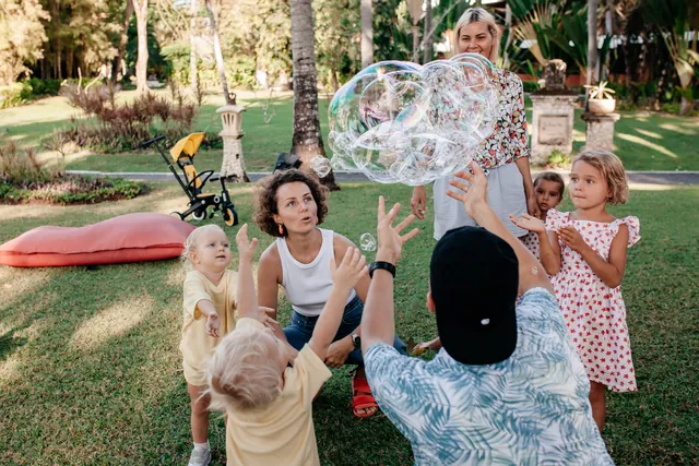 Families playing with giant soap bubbles on a Bali villa lawn