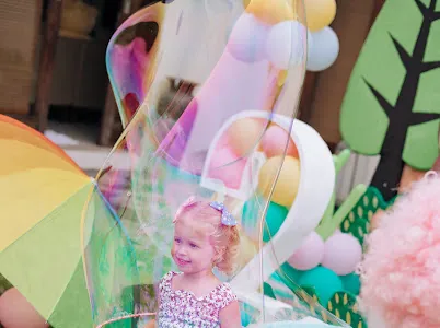 Girl watching a giant rainbow bubble at a kids party in Bali