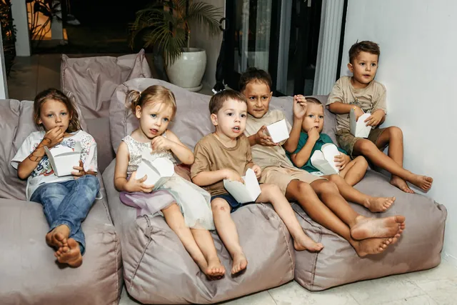 Kids with popcorn boxes relaxing on beanbags at a party