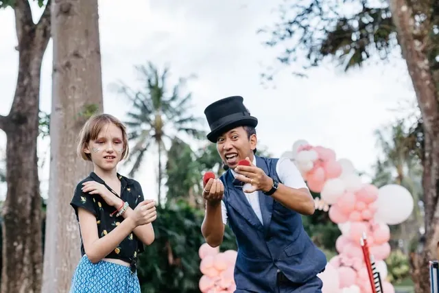 Magician showing a trick to a young guest at a Bali party