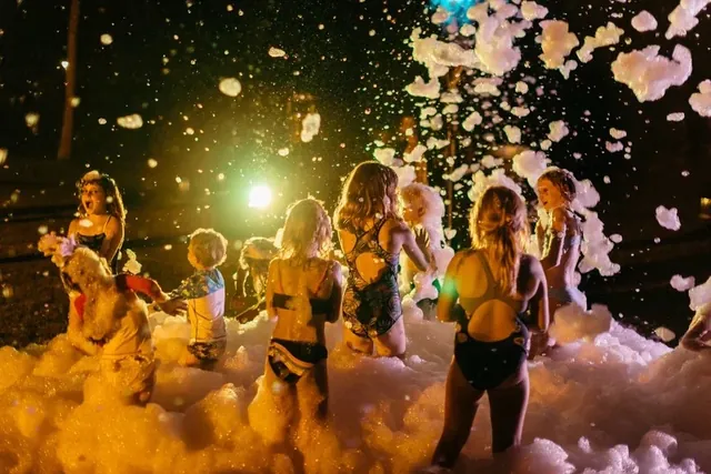 Kids dancing in neon-lit foam at an evening party in Bali