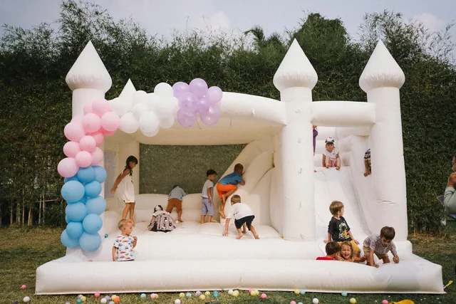 Kids playing in a white bounce castle with pastel balloons